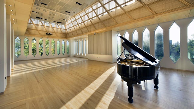 A grand piano in a large sunny room with many windows