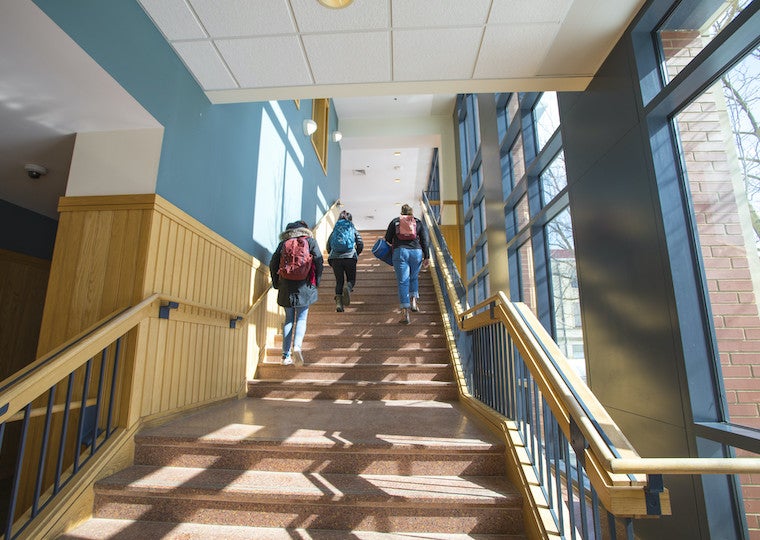 Students walk up stairs in a building.