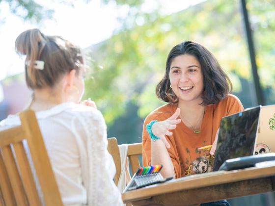 Two people meet at a table outdoors.