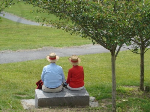 An older couple seated on a park bench