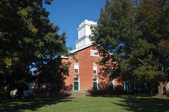 A view of First Church from the front. The building is brick and is shaped like a barn with a white tower