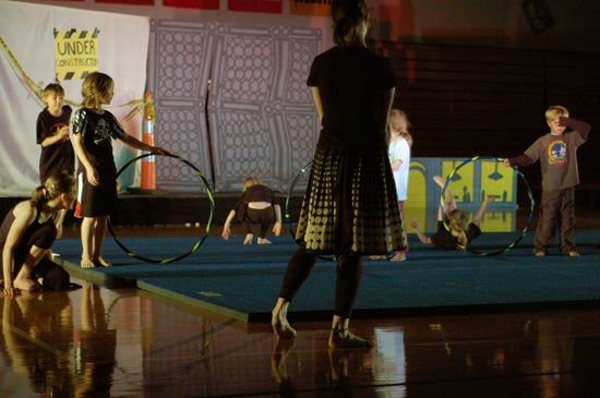 Children hold hoola hoops on a gym mat 
