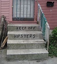 Front door of a house with a stoop with the words "keep off hipsters" written on the steps.
