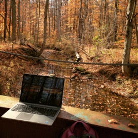an open laptop by a stream