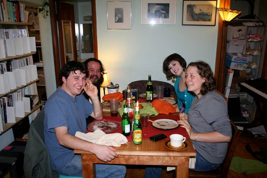 4 people enjoying a meal in a small apartment.