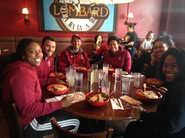 A group of people in Oberlin clothing are seated around a table at a restaurant