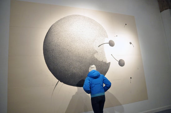 A viewer stands in front of an artwork