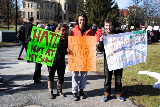 Three students hold protest sign: "There is no place for hate on this campus"