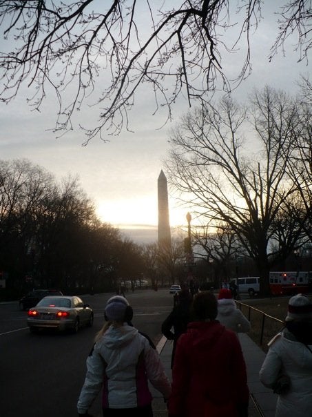 Walking along a busy road, where the sun is rising behind the Washington Monument