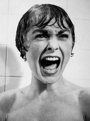 A still from a horror film of a woman in a shower screaming
