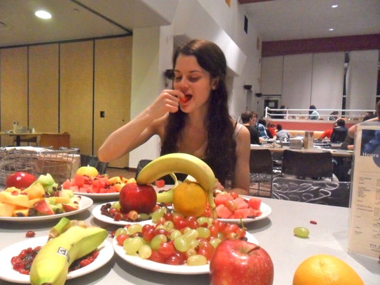 Student eating fruit with plates full of fruit on the table