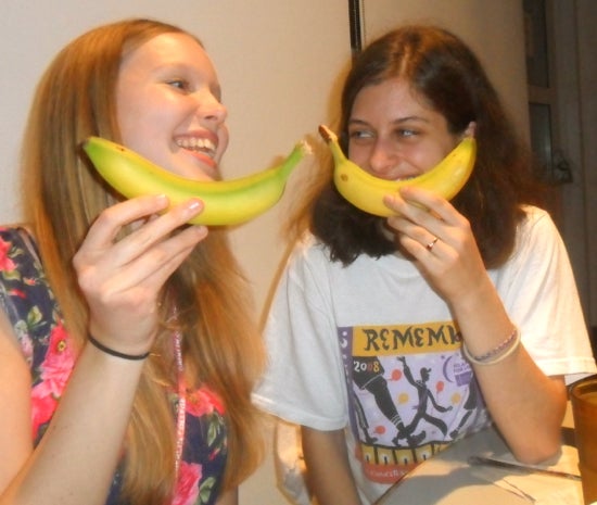 Two students smiling and holding bananas like smiles