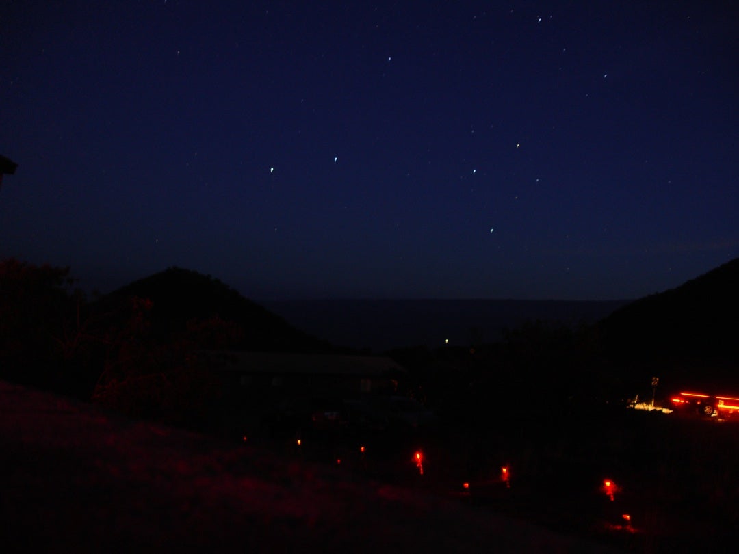 Starry sky above silhouetted mountains and the sea