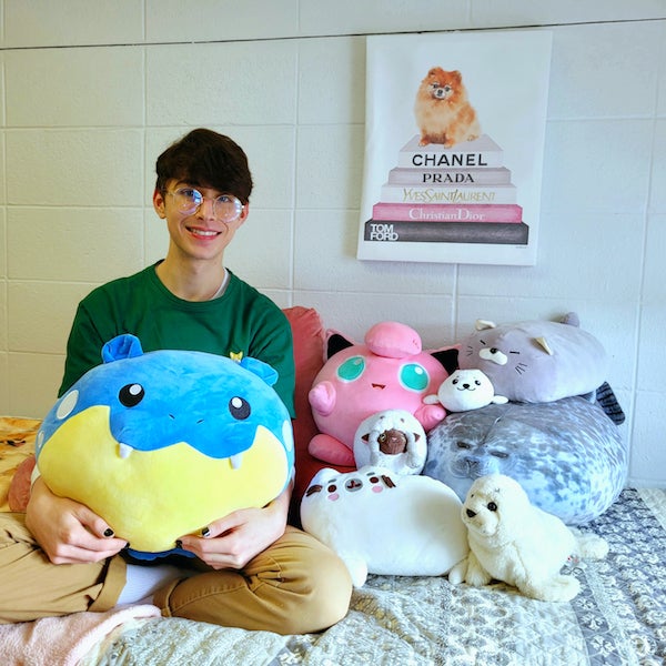 Me sitting on my bed with 8 stuffed animals: 3 Pokémon, 4 seals, and 1 cat.