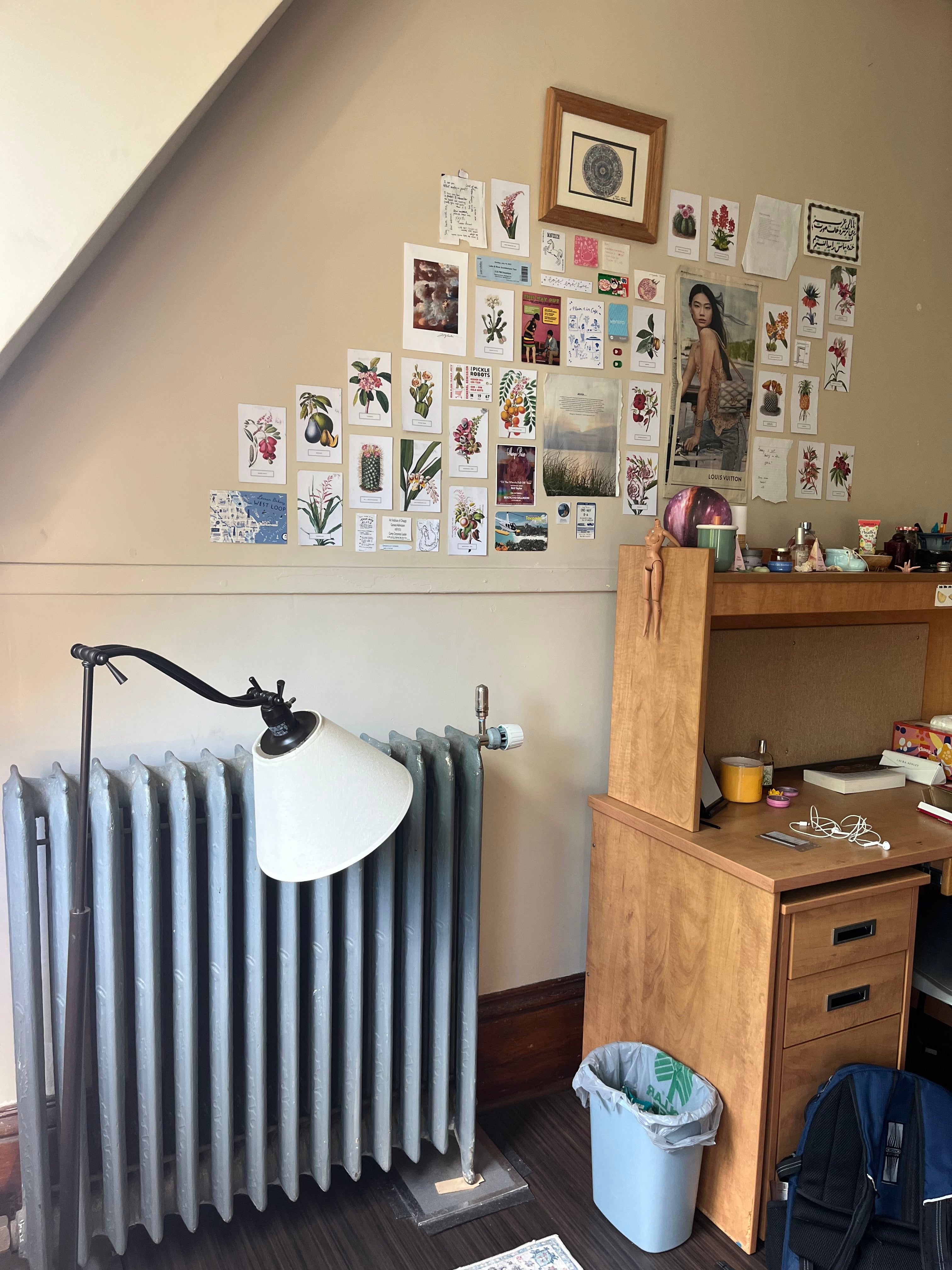 A wall of posters and a desk and a radiator