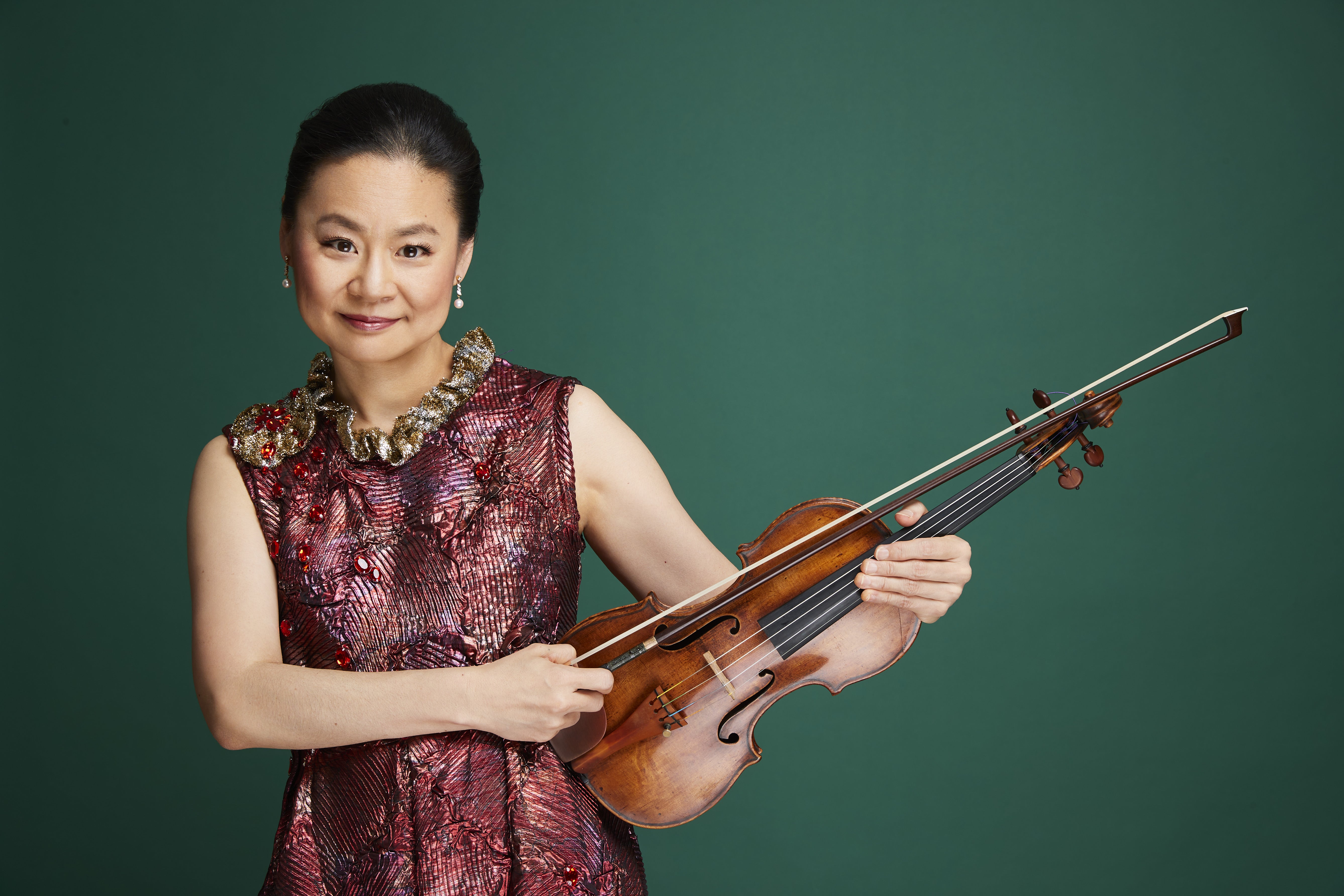 a woman holding a violin with a green background