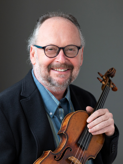 man with glasses wearing suitcoat and blue shirt, holding violin