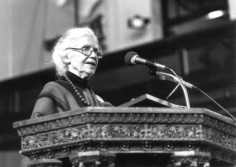 An elderly woman speaks at a podium.