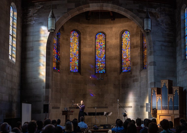 A flutist plays in a stone church.