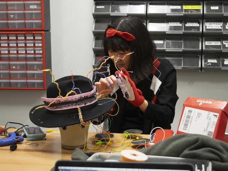A girl places flexible wires on a hat.