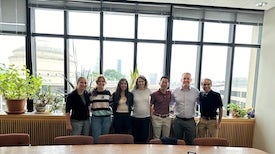 Group poses in front of window.