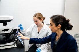 Two scientists use microscope.