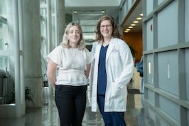 Two women in medical building hallway. 