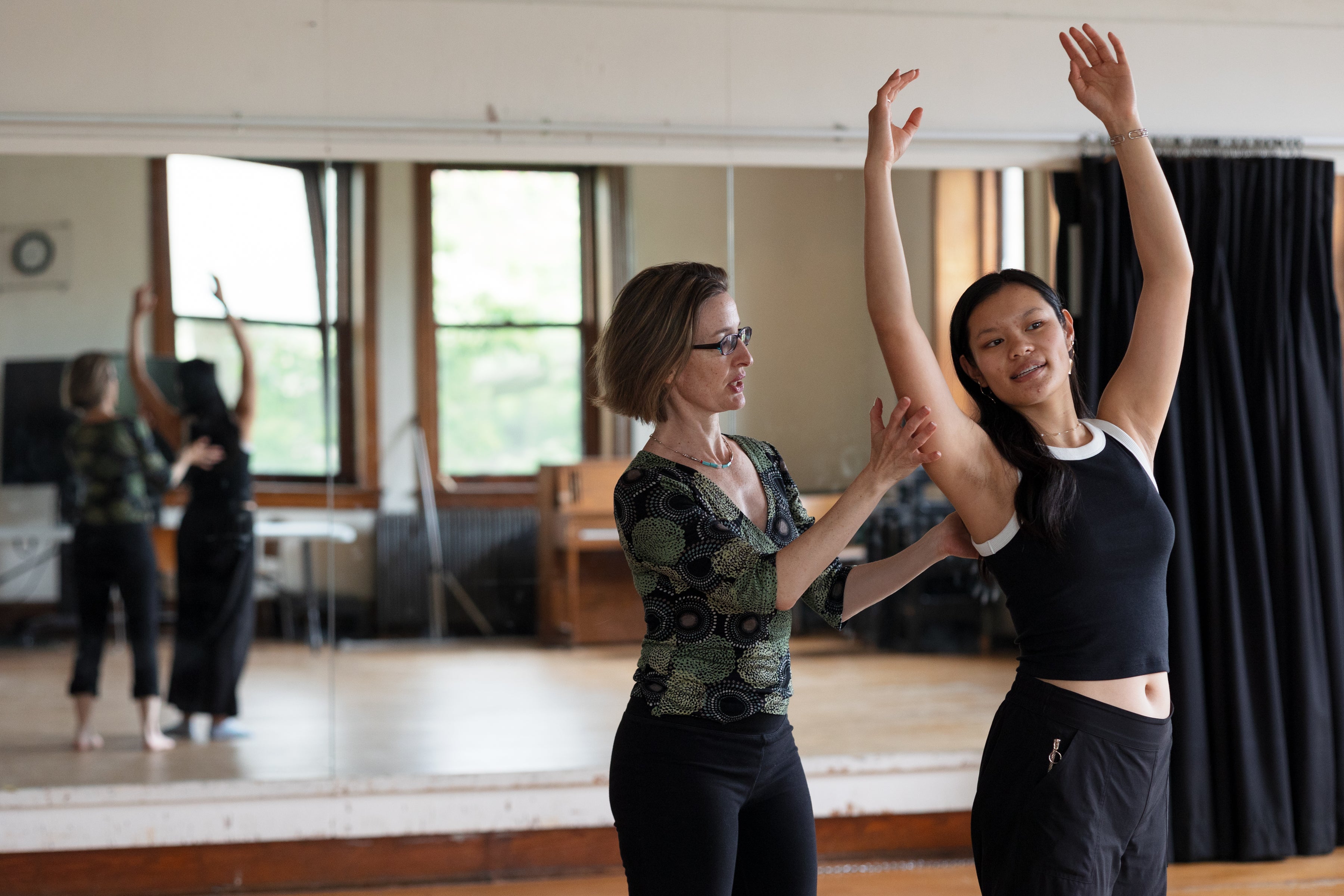Faculty instructs dance student in sunlight studio.