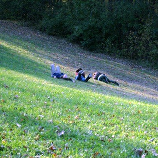 Three friends lay in the grass on a hillside.