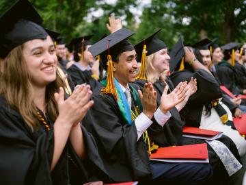 Seated students applaud during commencement addresses.