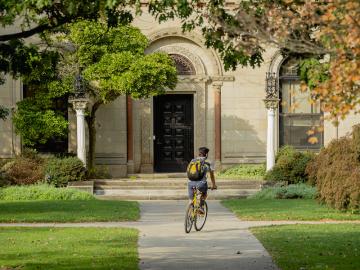 bicycle rider making a turn in front of Cox Administration Building.