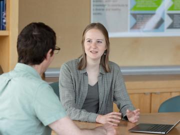 a student works with a professor at a table