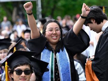 a student raises their fists in triumph during commencement