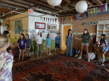 College interns and younger children stand in a circle