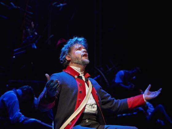 A performer sings under stage lights.