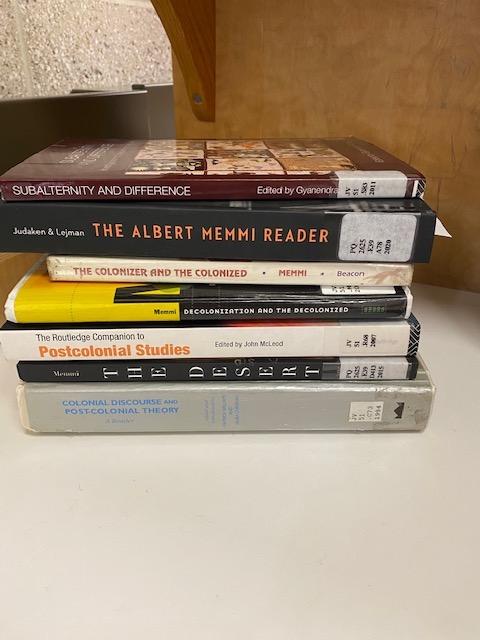 A stack of books including Subalternity and Difference, The Colonizer and the Colonized, and Postcolonial Studies.