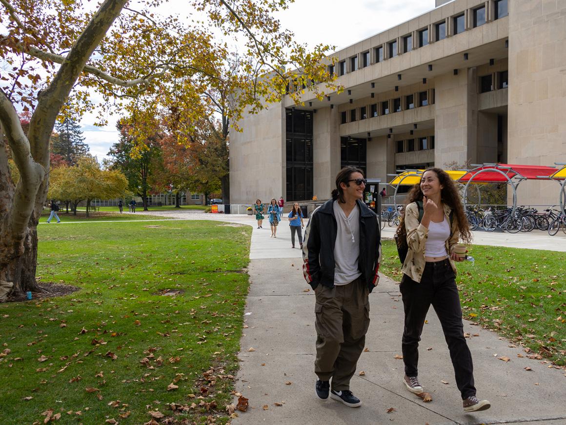 Students converse while walking past the Mudd Center.