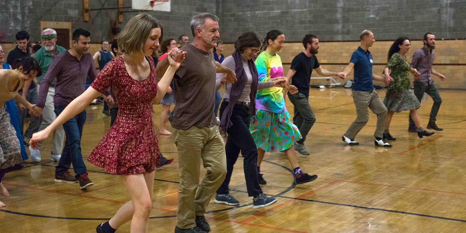 People dancing in a line in a gymnasium.