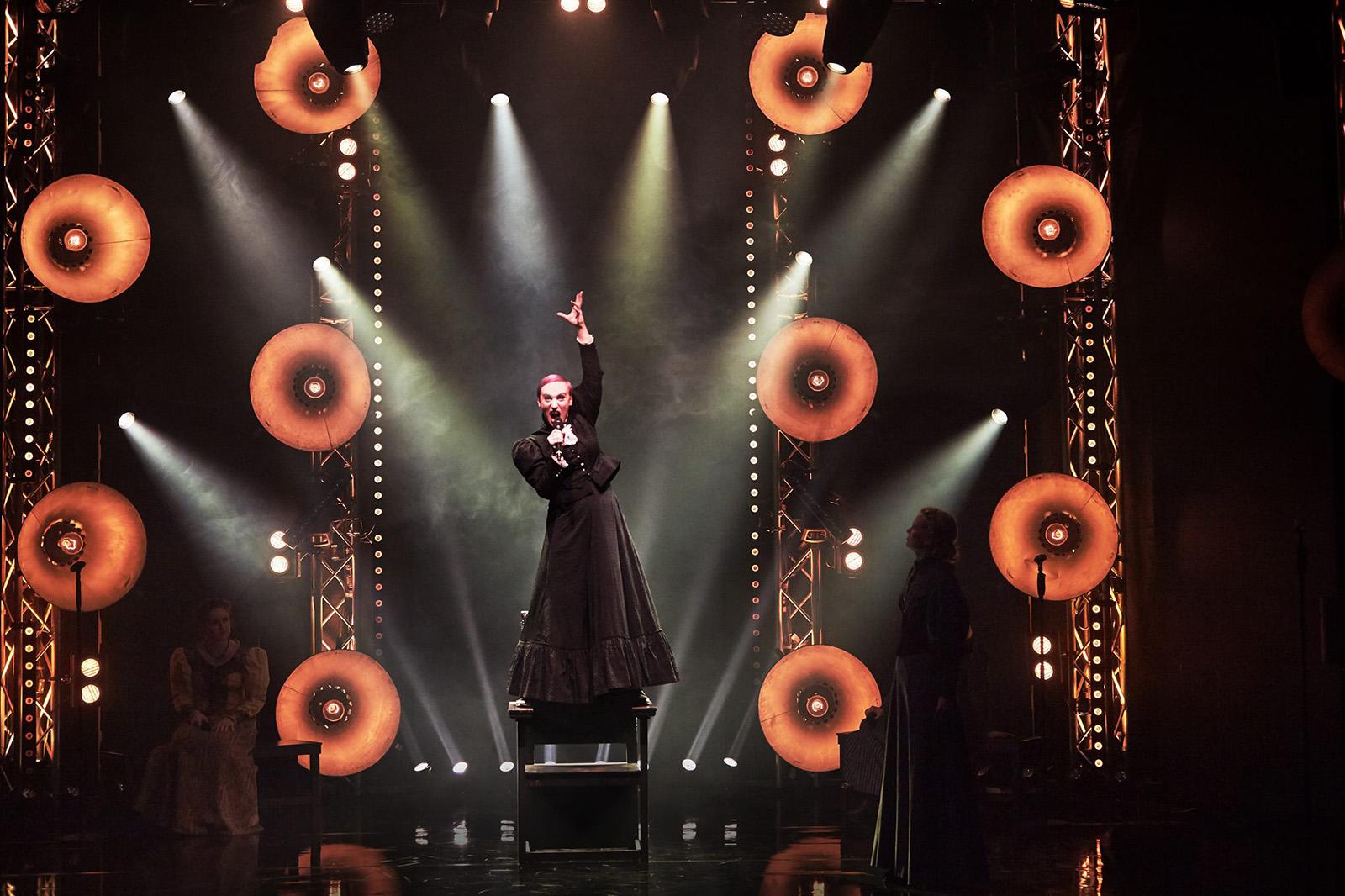 A singer performs in costume under stage lights.