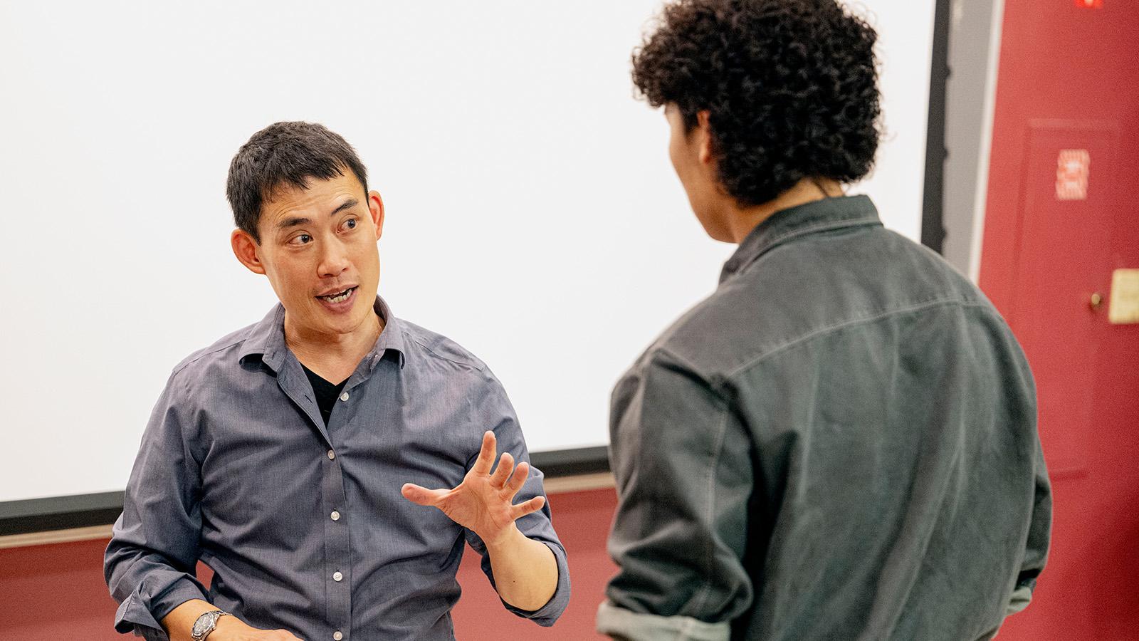 Professor speaks to student at front of class.