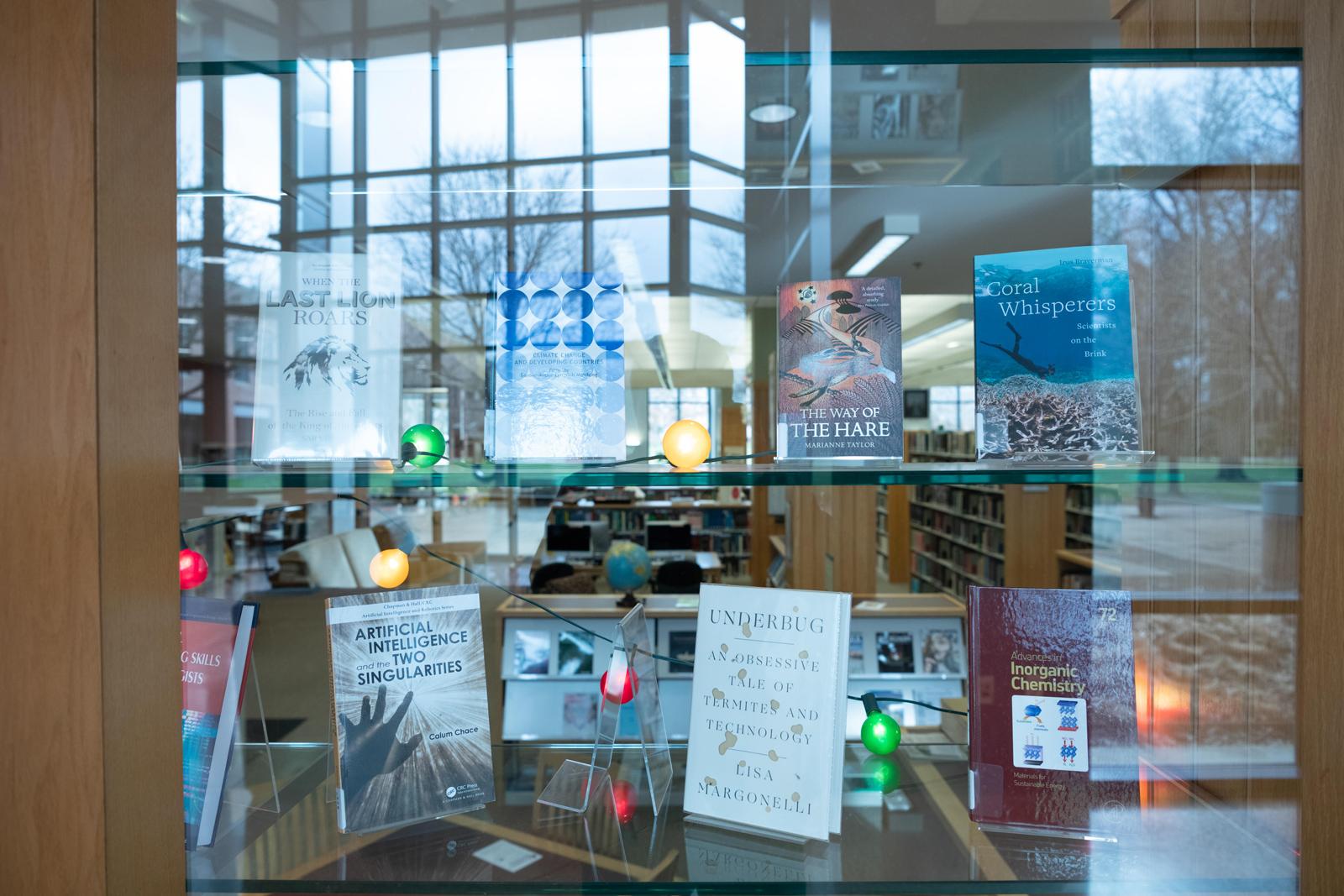 Books are displayed in a glass case in a modern library.