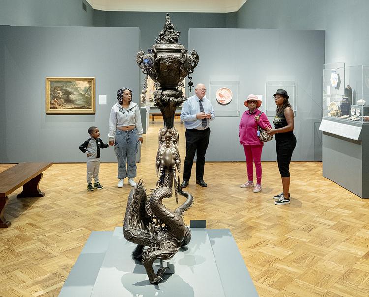 A family of four standing at the bronze dragon with a museum curator.