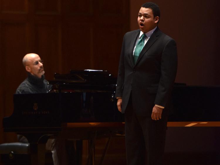 adult man at piano accompanies young black male singer