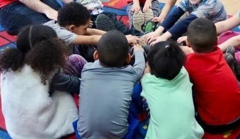 Circle of children putting hands together