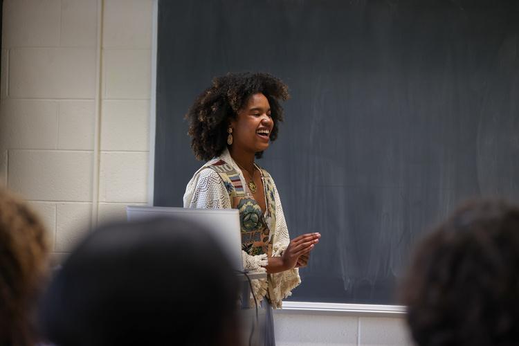Student presenter speaking in front of a blackboard. 
