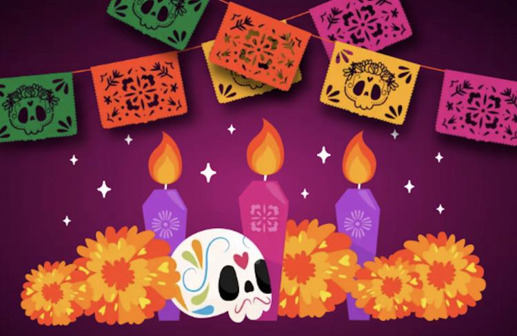 A sugar skull surrounded with flowers, candles and decorated paper flags