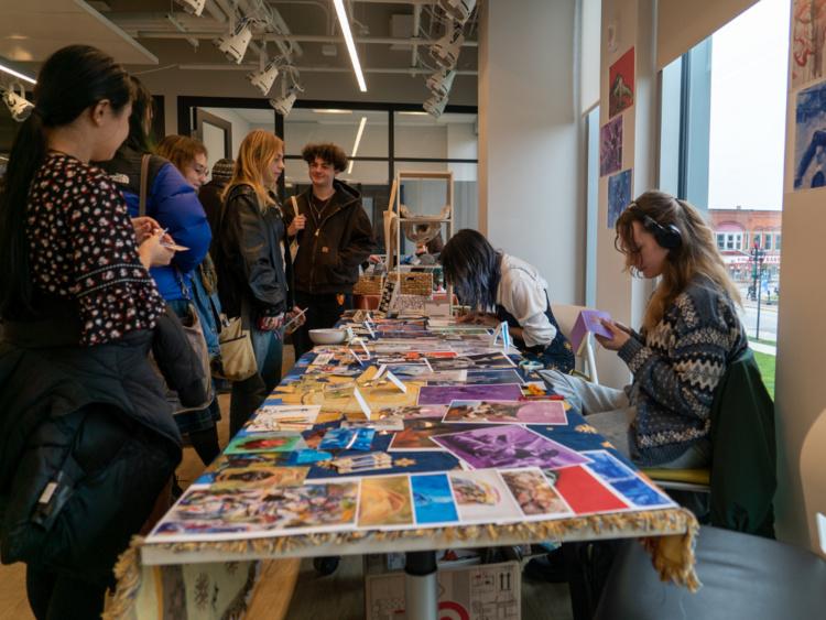 People looking at art on a vendor table, photo from previous art market event