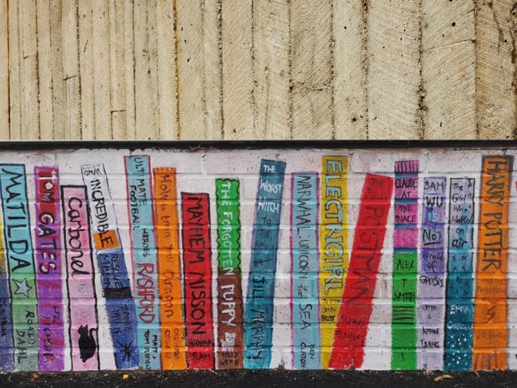 Chalk drawing of books on a brick wall