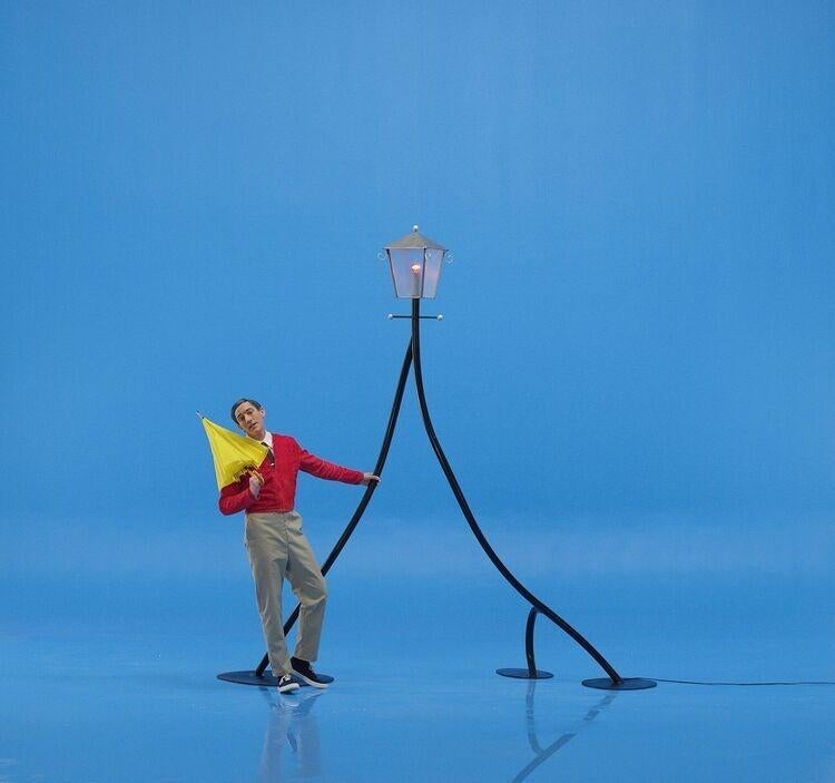 Person holding a yellow umbrella under a stylized street lamp