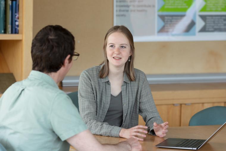 a student works with a professor at a table